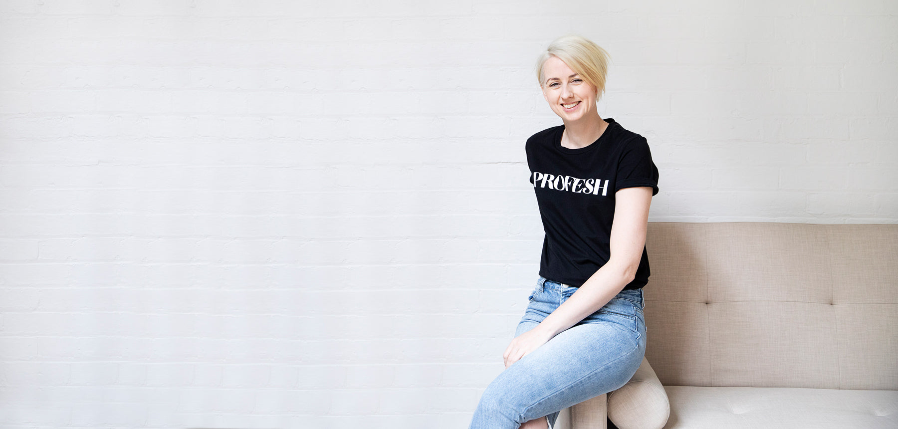 Model wearing Black Slogan tshirt reseting on a beige couch