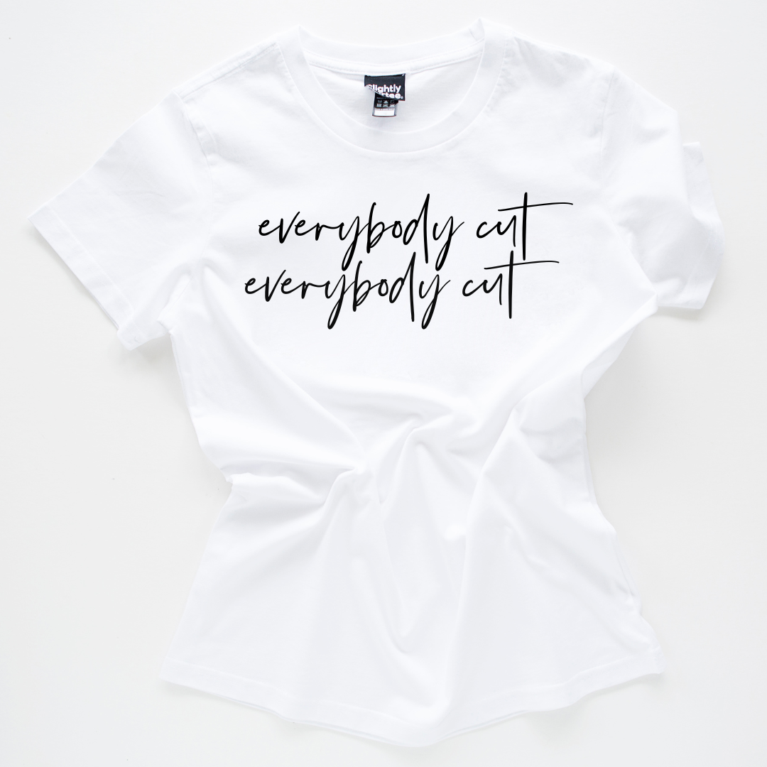 White slogan tee on a white background. Slogan says everybody cut as a reference to the 80s movie footloose. Tee is crumpled up in the centre